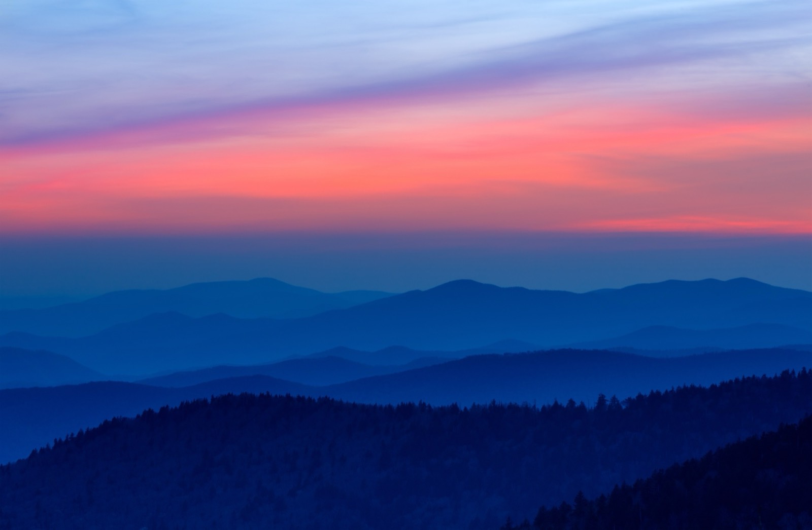 Layer after layer of blue mountain ridges fading into a soft pink and violet dusk sky
